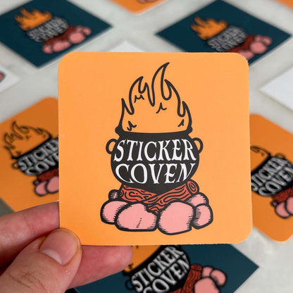 rounded square cut sticker featuring a graphic of a cauldron on a campfire with text "Sticker Coven" on a yellow background